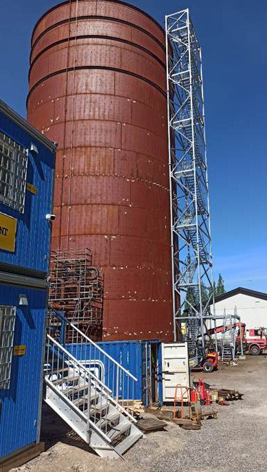 A large silo with a blue ladder Description automatically generated with medium confidence